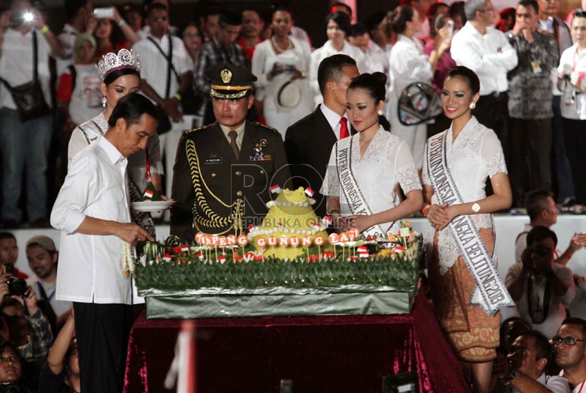  Presiden Jokowi memotong tumpeng pada Konser Salam 3 Jari di lapangan Monumen Nasional, Jakarta, Senin (20/10) malam.   (Republika/Yasin Habibi)