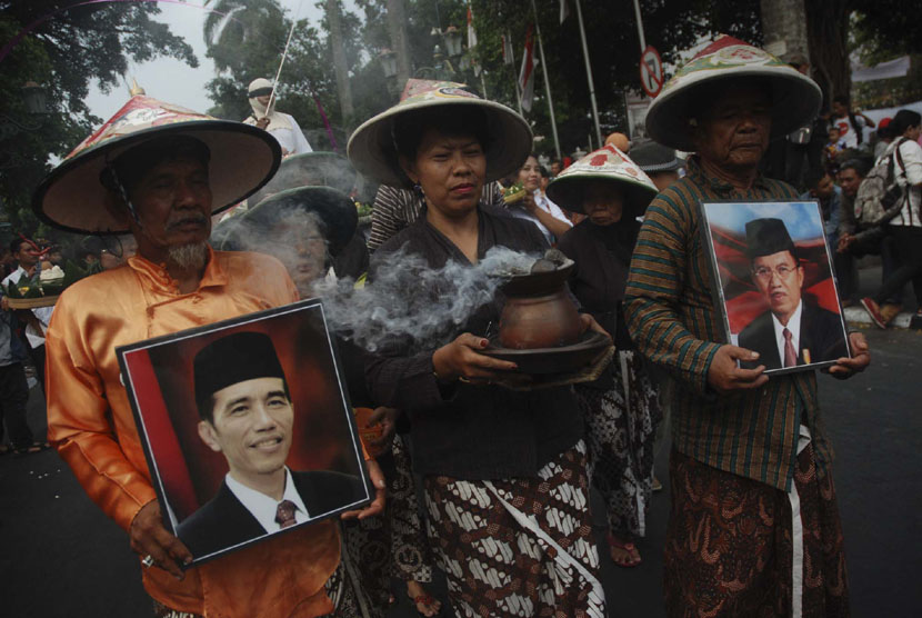 Sejumlah warga mengikuti prosesi kirab penyambutan Presiden ke-7 RI Jokowi di kawasan Nol Kilometer Yogyakarta, Senin (20/10).