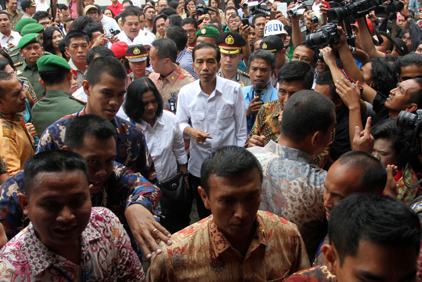   Presiden Joko Widodo (tengah) didampingi Ibu Negara Iriana Joko Widodo (ketiga kiri) berjalan ketika tiba di lokasi pengungsian erupsi Gunung Sinabung, Karo, Sumut, Rabu (29/10).(Antara/Irsan Mulyadi)