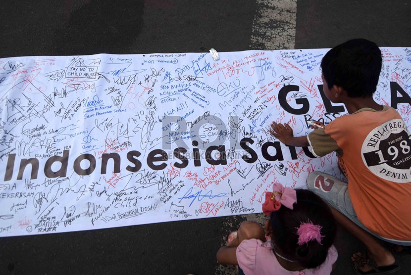  Seorang anak menandatangani spanduk panjang saat aksi menentang kekerasan kepada anak di Jakarta, Ahad (2/11).  (Republika/Agung Supriyanto)