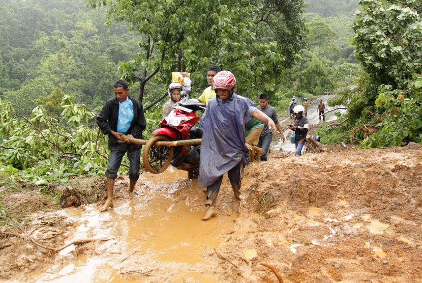  Warga membantu mengangkat sepedamotor pengguna jalan saat menerobos jalur longsor yang menimbun badan jalan di kawasan pegunungan Paro, kecamatan Leupung, Aceh Besar, Aceh, Senin (3/11). (Antara/Ampelsa)