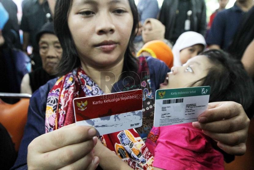   Warga menunjukkan Kartu Indonesia Sehat (KIS) dan Kartu Keluarga Sejahtera (KKS) saat peluncuran kartu tersebut dan Kartu Indonesia Pintar di Kantor Pos Besar, Jakarta Pusat, Senin (3/11).  (Republika/ Yasin Habibi)