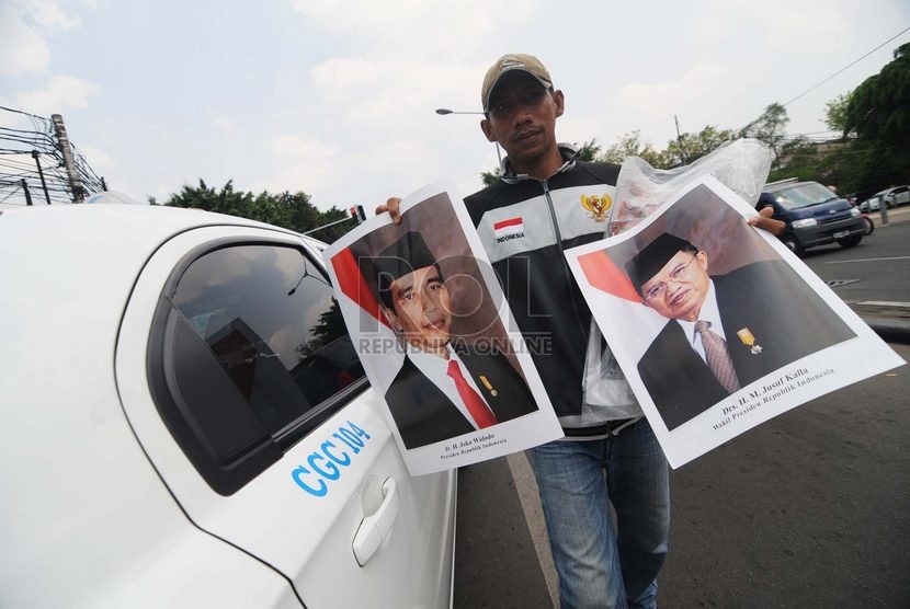   Seorang pedagang menjajakan poster Presiden Joko Widodo dan Wakil Presiden Jusuf Kalla di Kawasan Menteng, Jakarta Pusat, Senin (3/11). ( Republika/Raisan Al Farisi)