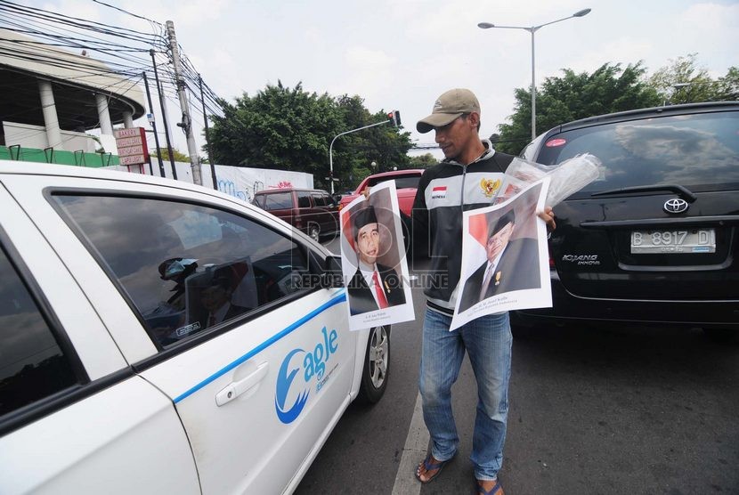   Seorang pedagang menjajakan poster Presiden Joko Widodo dan Wakil Presiden Jusuf Kalla di Kawasan Menteng, Jakarta Pusat, Senin (3/11). ( Republika/Raisan Al Farisi)