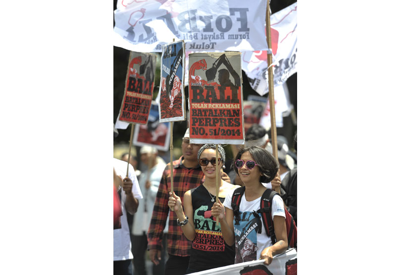   Dua pengunjuk rasa memajang poster untuk menolak rencana revitalisasi Teluk Benoa saat aksi unjuk rasa tolak reklamasi di depan Kantor Gubernur Bali, Denpasar, Selasa (4/11).  (Antara/Nyoman Budhiana)