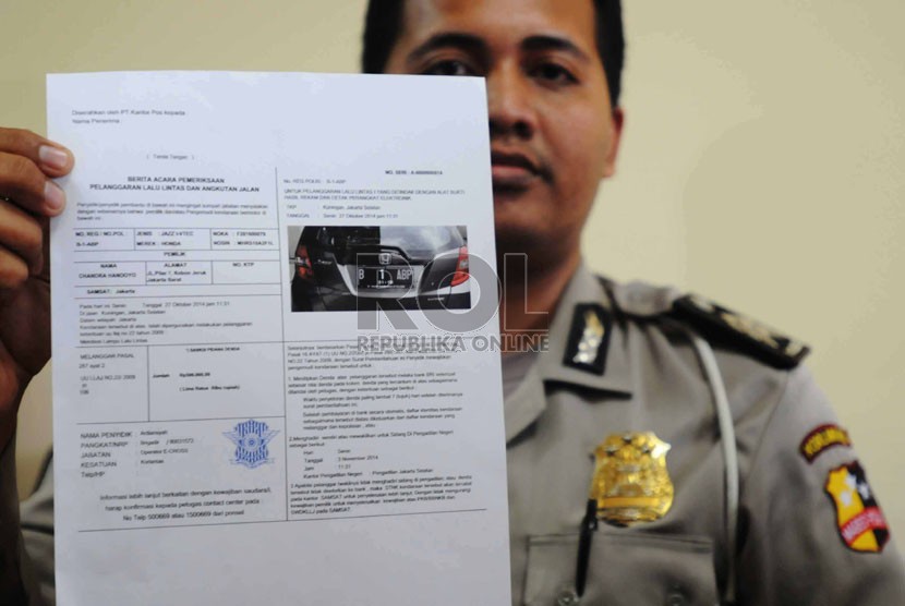 Petugas operator menunjukkan surat tilang bukti pelanggaran lalulintas. 