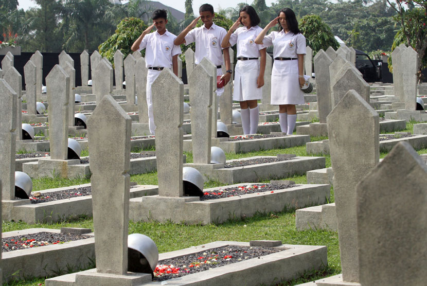 Four students give salute after sowing flowers at National Heroes Cemetary in Kalibata, Jakarta, on Monday, Nov 10.