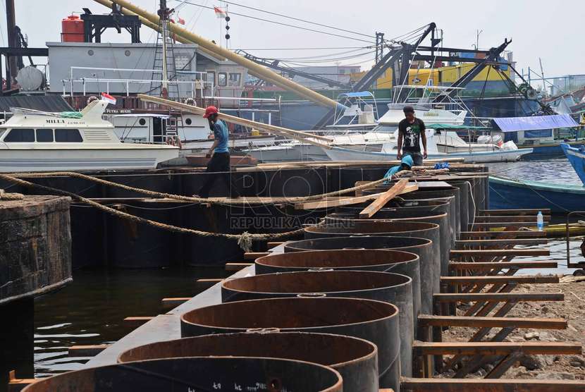  Pekerja mengerjakan proyek untuk tanggul penahan ombak di kawasan Pompa Air waduk Pluit, Jakarta Utara, Senin (24/11).  (Republika/ Tahta Aidilla)