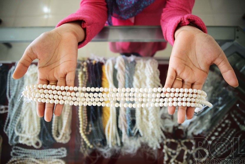   Penjual menunjukkan perhiasan berupa mutiara air tawar yang dijual di sentra pusat perhiasan mutiara di Kawasan Sekarbela, Mataram, Nusa Tenggara Barat, Ahad (21/12).( Republika/Raisan Al Farisi)