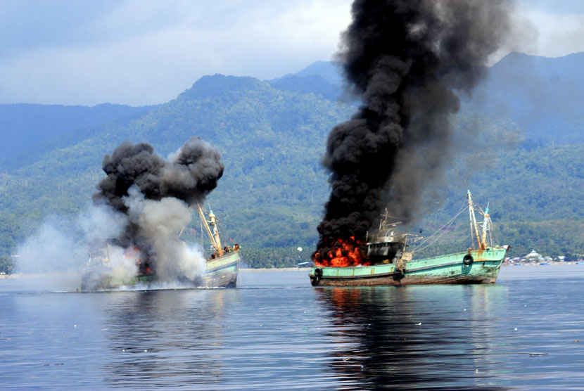 Dua kapal ikan ilegal berbendera Papua Nugini meledak dan mengeluarkan api ketika ditenggelamkan personel Lantamal IX Ambon di Perairan Teluk Ambon, Maluku, Ahad (21/12). (Antara/Izaac Mulyawan)