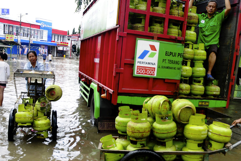   Warga membawa sejumlah tabung gas elpiji 3 kg melewati genangan banjir di Jalan Raya Dayeuhkolot, Kabupaten Bandung, Jawa Barat, Ahad (21/12). (Antara/Novrian Arbi)