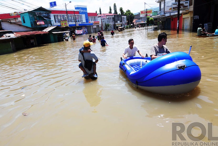   Sejumlah warga melintasi banjir di Jalan Dayeuhkolot, Kabupaten Bandung, Kamis(25/12).  (foto: Septianjar Muharam)