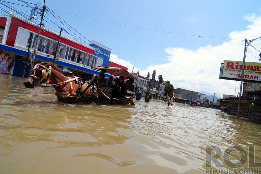    Sejumlah warga melintasi banjir di Jalan Dayeuhkolot, Kabupaten Bandung, Kamis(25/12).  (foto: Septianjar Muharam)