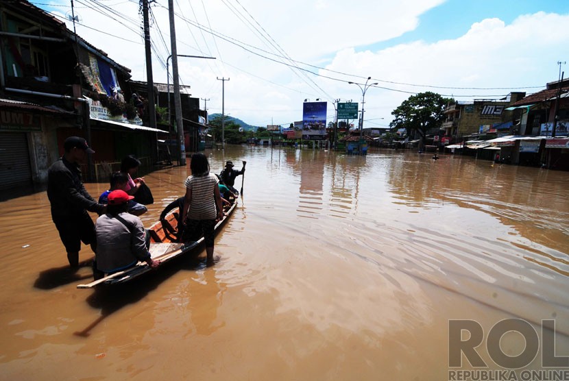 Warga menaiki ojeg perahu saat melintasi banjir di Jalan Raya Banjaran, Kabupaten Bandung, Kamis(25/12). (foto: Septianjar Muharam)