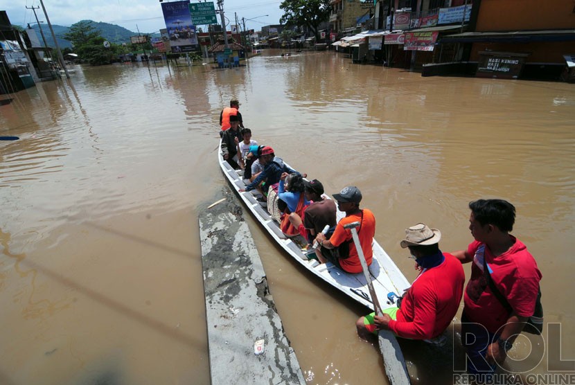 Warga menaiki ojeg perahu saat melintasi banjir di Jalan Raya Banjaran, Kabupaten Bandung, Kamis(25/12). (foto: Septianjar Muharam)