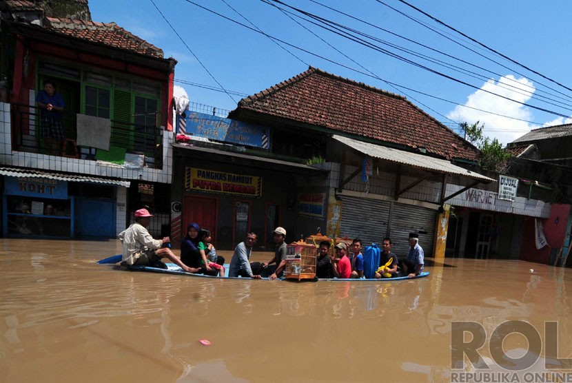 Warga menaiki ojeg perahu saat melintasi banjir di Jalan Raya Banjaran, Kabupaten Bandung, Kamis(25/12). (foto: Septianjar Muharam)