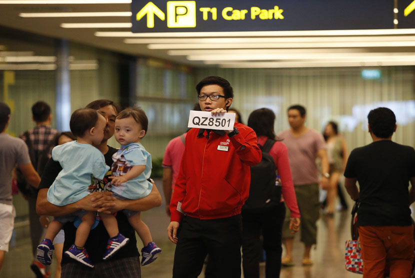  Petugas bandara Changi memegang tanda nomor penerbangan maskapai Air Asia QZ 8501 yang hilang kontak dalam perjalanan dari Surabaya menuju Singapura, Ahad (28/12). (Reuters/Edgar Su)