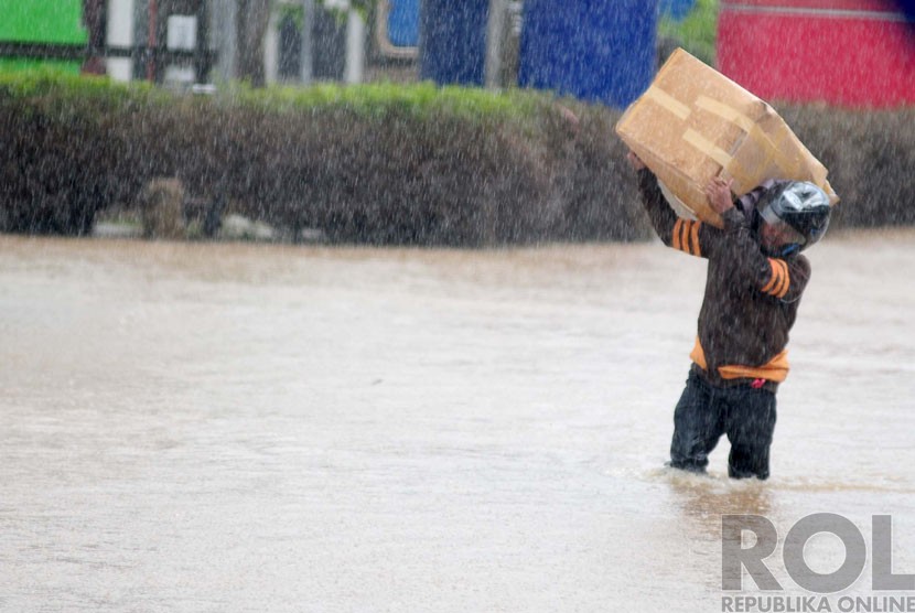  Warga melintasi banjir di Andir, Dayeuhkolot, Kabupaten Bandung, Ahad(28/12). (foto : Septianjar Muharam)