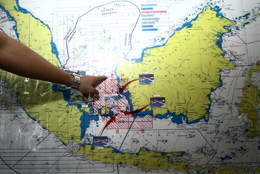 An Indonesian Navy personnel points location of seacprching the missing AirAsia flight QZ8501 on the map on Monday.