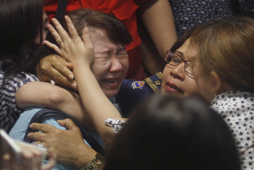   Keluarga penumpang pesawat AirAsia QZ 8501, menangis histeris saat mendengar kabar ditemukannya serpihan pesawat, di Bandara Internasional Juanda, Surabaya, Selasa (30/12). (AP/Trisnadi)