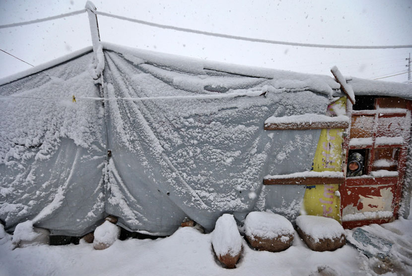   Seorang anak berdiri di pintu tenda kamp pengungsi asal Suriah di desa Deir Zannoun, lembah Bekaa, Lebanon, Rabu (7/1). (AP/Hussein Malla)