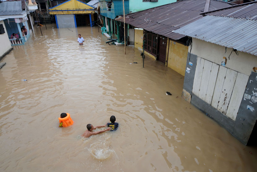  Beberapa anak bermain air didepan rumanya ketika banjir merendam rumahnya di kelurahan Ternate Tanjung, Manado, Sulawesi Utara, Ahad (11/1). (Antara/Fiqman Sunandar)