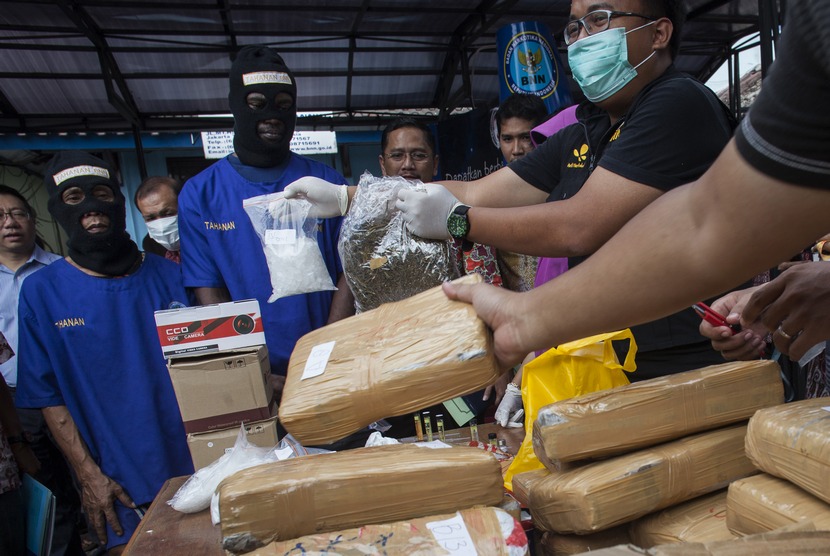  Petugas Badan Narkotika Nasional (BNN) menunjukkan barang bukti ganja yang disita dari tangan tersangka berinisial MU (kanan) sebelum dimusnahkan di Kantor BNN, Jakarta Timur, Jumat (16/1). (Antara/Sigid Kurniawan)