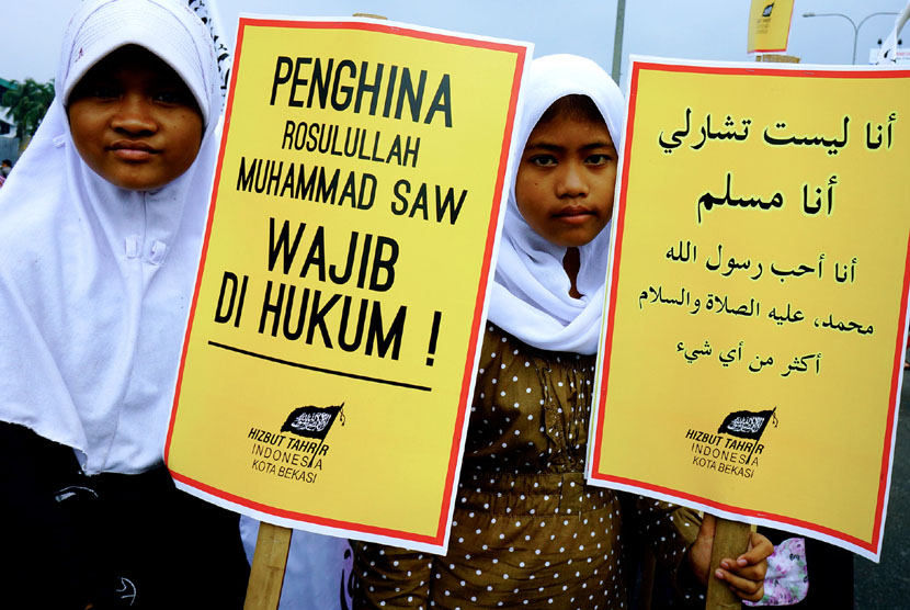 Massa dari Hizbut Tahrir Indonesia (HTI) Kota Bekasi membawa poster ketika menggelar dakwah dengan tema Saya bukan Charlie pada hari bebas kendaraan di Bekasi, Jawa Barat, Ahad (18/1).