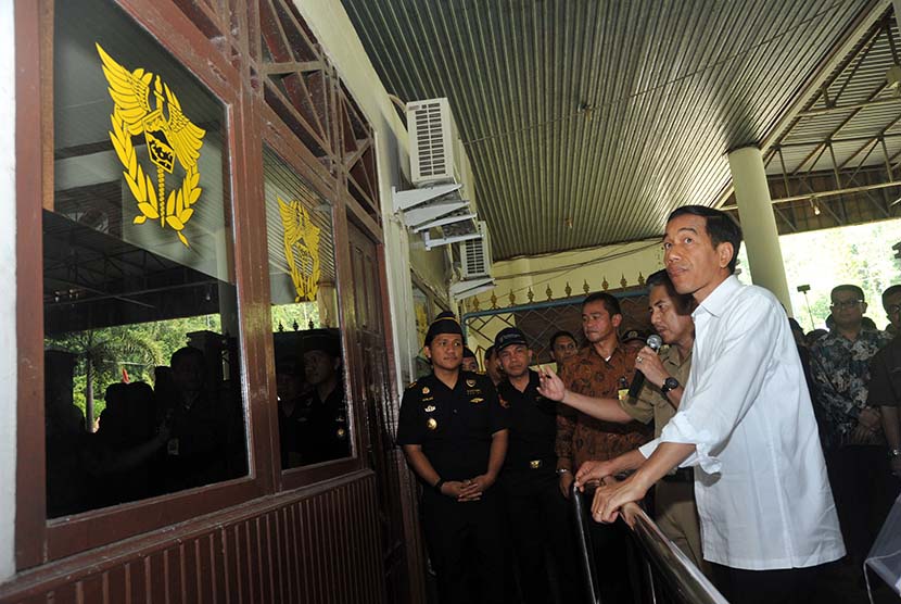   Presiden Joko Widodo (kanan) mendengarkan pemaparan dari petugas perbatasan saat meninjau kondisi Pos Pemeriksaan Lintas Batas (PPLB) Entikong di Kabupaten Sanggau, Kalbar, Rabu (21/1).   (Antara/Jessica Helena Wuysang)