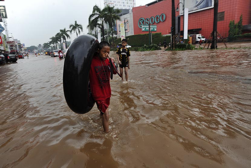 Seorang anak membawa ban ketika banjir melanda Kawasan Kelapa Gading Jakarta, Jumat (23/1).  (Antara/Wahyu Putro)     