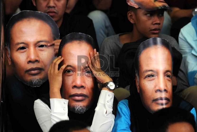  Piuluhan warga yang tergabung dalam Gerakan Rakyat Melawan Korupsi mengenakan topeng berwajah Wakil Ketua KPK, Bambang Widjojanto saat menggelar aksi di depan Gedung KPK, Jakarta, Sabtu (24/1). (Republika/Agung Supriyanto)