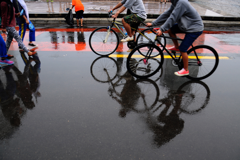  Warga bersepeda kala hujan. Berolahraga dan konsumsi multivitamin bisa jadi cara tingkatkan kekebalan saat cuaca dingin di musim hujan