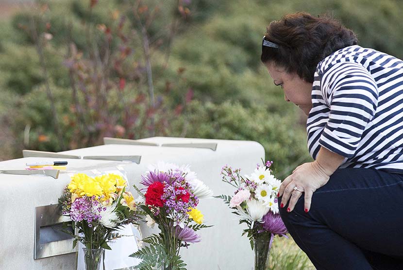  Seorang wanita melihat bunga yang diletakan untuk mengenang tiga mahasiswa muslim korban penembakan, di Universitas North Carolina, Chapel Hill, Rabu (11/2) waktu setempat. (REUTERS/Chris Keane)