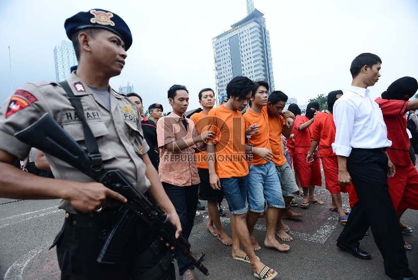 Seorang anggota kepolisian mengawal pelaku tindak kriminal