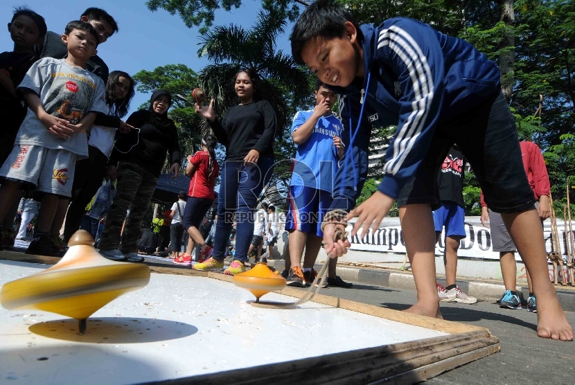 Sejumlah warga mencoba permainan gangsing yang diadakan oleh Kampoeng Dolanan Nusantara saat Car Free Day di Jakarta, Ahad (22/2).    (Republika/Agung Supriyanto)