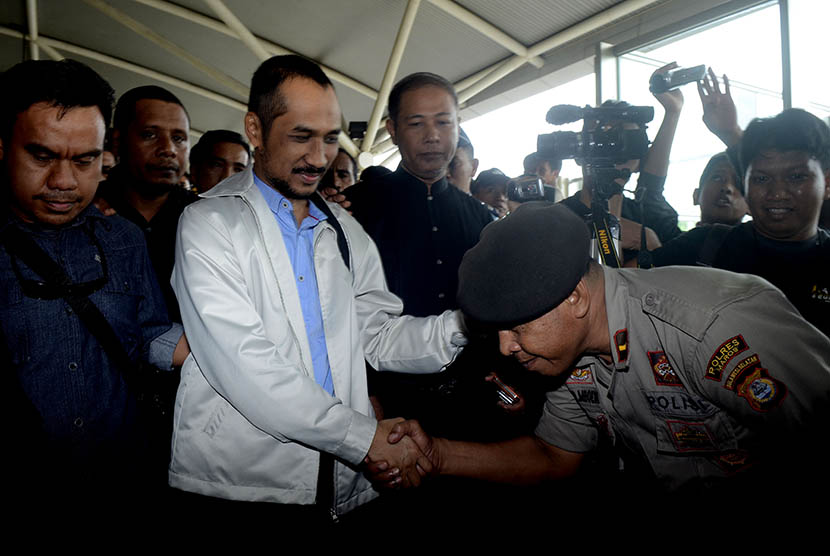 Ketua  KPK non aktif , Abraham Samad (kanan) bersalaman dengan polisi saat tiba di Bandar Udara Internasional Sultan Hasanuddin, Makassar, Sulawesi Selatan, Selasa (24/2).  (Antara/Sahrul Manda Tikupadang)