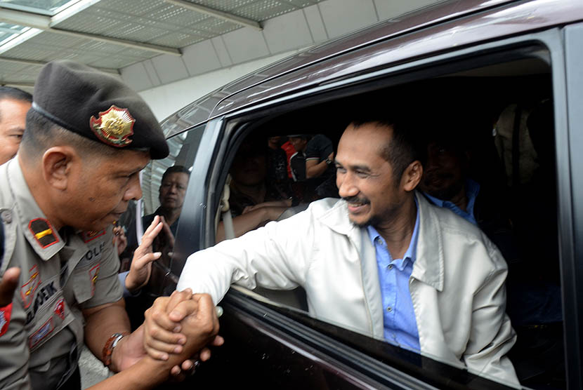 Ketua  KPK non aktif , Abraham Samad (kanan) bersalaman dengan polisi saat tiba di Bandar Udara Internasional Sultan Hasanuddin, Makassar, Sulawesi Selatan, Selasa (24/2).  (Antara/Sahrul Manda Tikupadang)