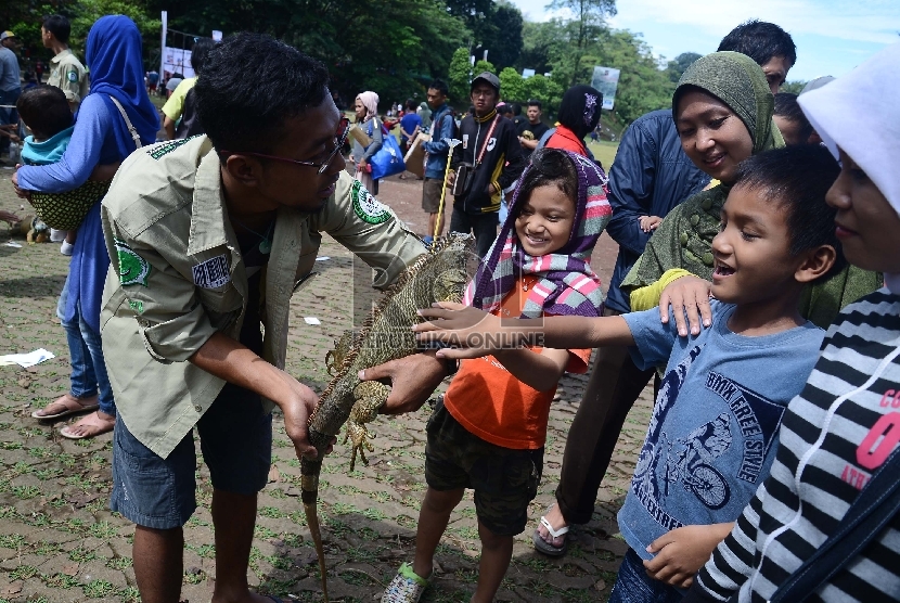 Anggota Komunitas Iguana Jabodetabek menunjukkan reptil jenis Iguana kepada seorang anak saat sosialisasi binatang jenis reptil di Car Free Day (CFD) Jalan Raya Sempur, Bogor, Ahad (15/3). (Republika/Raisan Al Farisi)