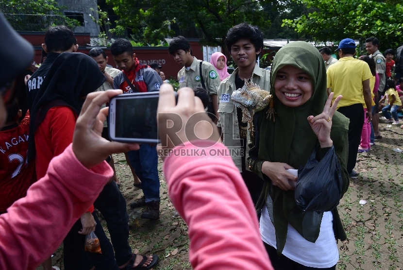 Warga berfoto bersama Reptil jenis iguana saat sosialisasi binatang jenis reptil di Car Free Day (CFD)  Jalan Raya Sempur, Bogor, Ahad (15/3). (Republika/Raisan Al Farisi)