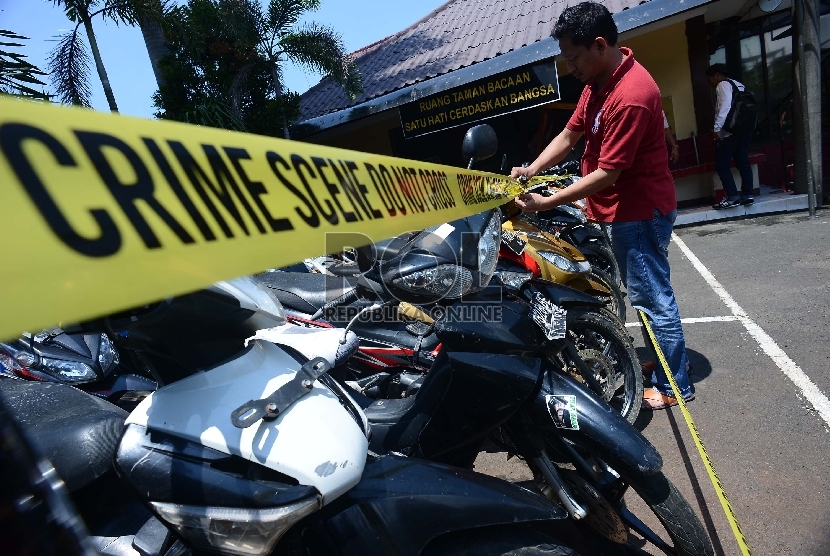  Anggota kepolisian memasangkan garis polisi di barang bukti sepeda motor sesaat sebelum rilis pengungkapan kasus begal di lapangan parkir Polres Metro Penjaringan, Jakarta Utara, Senin (16/3). (Republika/Raisan Al Farisi)