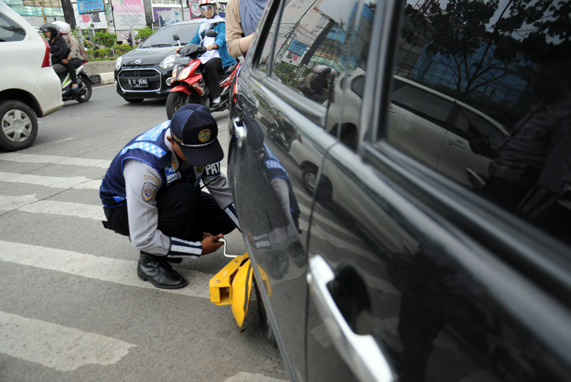 Petugas menggembok mobil yang diparkir sembarangan di jalan raya. ilustrasi  (Dok Republika)