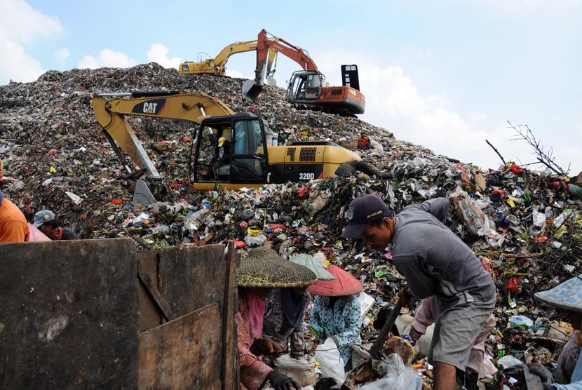 Pekerja menggunakan alat berat menumpuk sampah di TPA. Ilustrasi