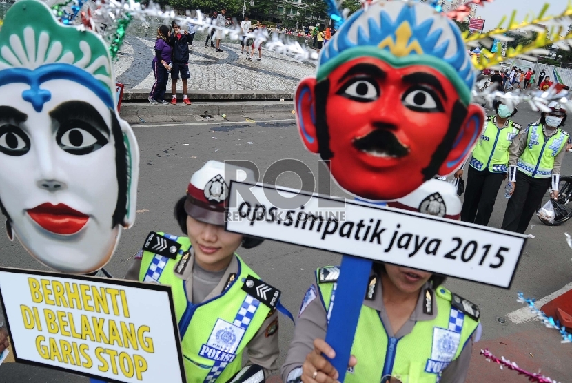 Polisi Wanita (Polwan) membawa ikon ondel-ondel saat sosialisasi operasi Simpatik Jaya 2015 di Car Free Day Bundaran HI,Jakarta, Ahad (5/4).  (Republika/Tahta Aidilla)