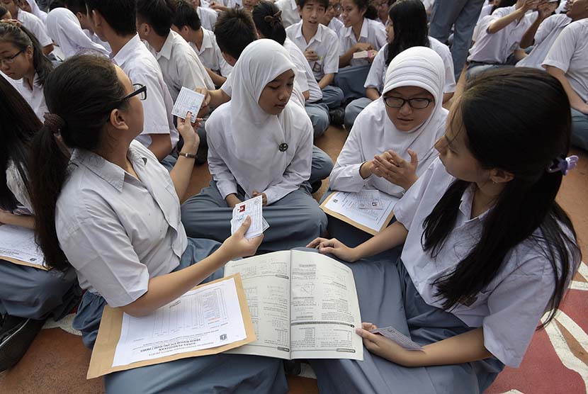    Peserta Ujian Nasional (UN)  menyempatkan diri untuk belajar saat menunggu kedatangan Presiden Joko Widodo di SMA N 2 Jakarta, Jakarta, Selasa (14/4).  (Antara/Sigid Kurniawan)