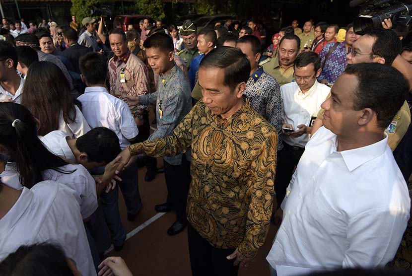   Presiden Joko Widodo (tengah) didampingi Menteri Kebudayaan dan Pendidikan Dasar dan Menengah Anies Baswedan (kanan) menyalami para peserta Ujian Nasional (UN) di SMA N 2 Jakarta, Jakarta, Selasa (14/4). (Antara/Sigid Kurniawan)