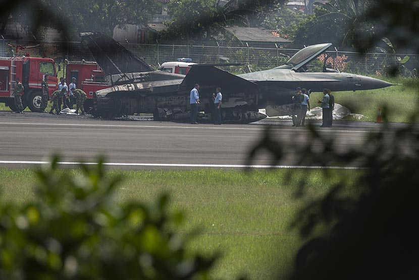 Sejumlah prajurit TNI AU berjaga di dekat badan pesawat tempur F16 yang terbakar di ujung landasan pacu Pangkalan Udara Halim Perdanakusuma, Jakarta Timur, Kamis (16/4).    (Antara/Rosa Panggabean)