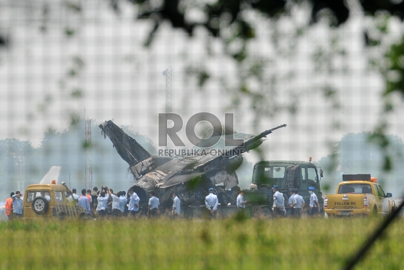 Sejumlah prajurit TNI AU melakukan proses evakuasi badan pesawat tempur F16 yang terbakar di ujung landasan pacu Pangkalan Udara Halim Perdanakusuma, Jakarta Timur, Kamis (16/4). (Republika/Edwin Dwi Putranto)