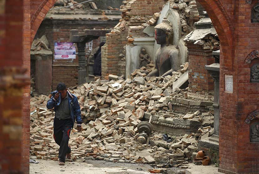  Seorang pria menangis saat melintasi reruntuhan sebuah kuil yang hancur akibat gempa bumi di Bhaktapur, Nepal, Ahad (26/4). (Reuters/Navesh Chitrakar)