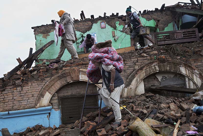 Warga mencari barang-barang dari reruntuhan rumah mereka yang hancur akibat gempa bumi di Kathmandu, Nepal, Senin (27/4). 