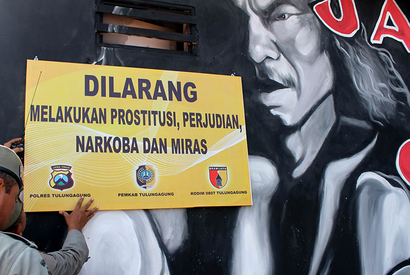  Petugas Satpol PP memasang papan pengumuman pelrangan prostitusi di kawasan eks-Lokalisasi Kaliwungu, Tulungagung, Jawa Timur, Jumat (8/5). 